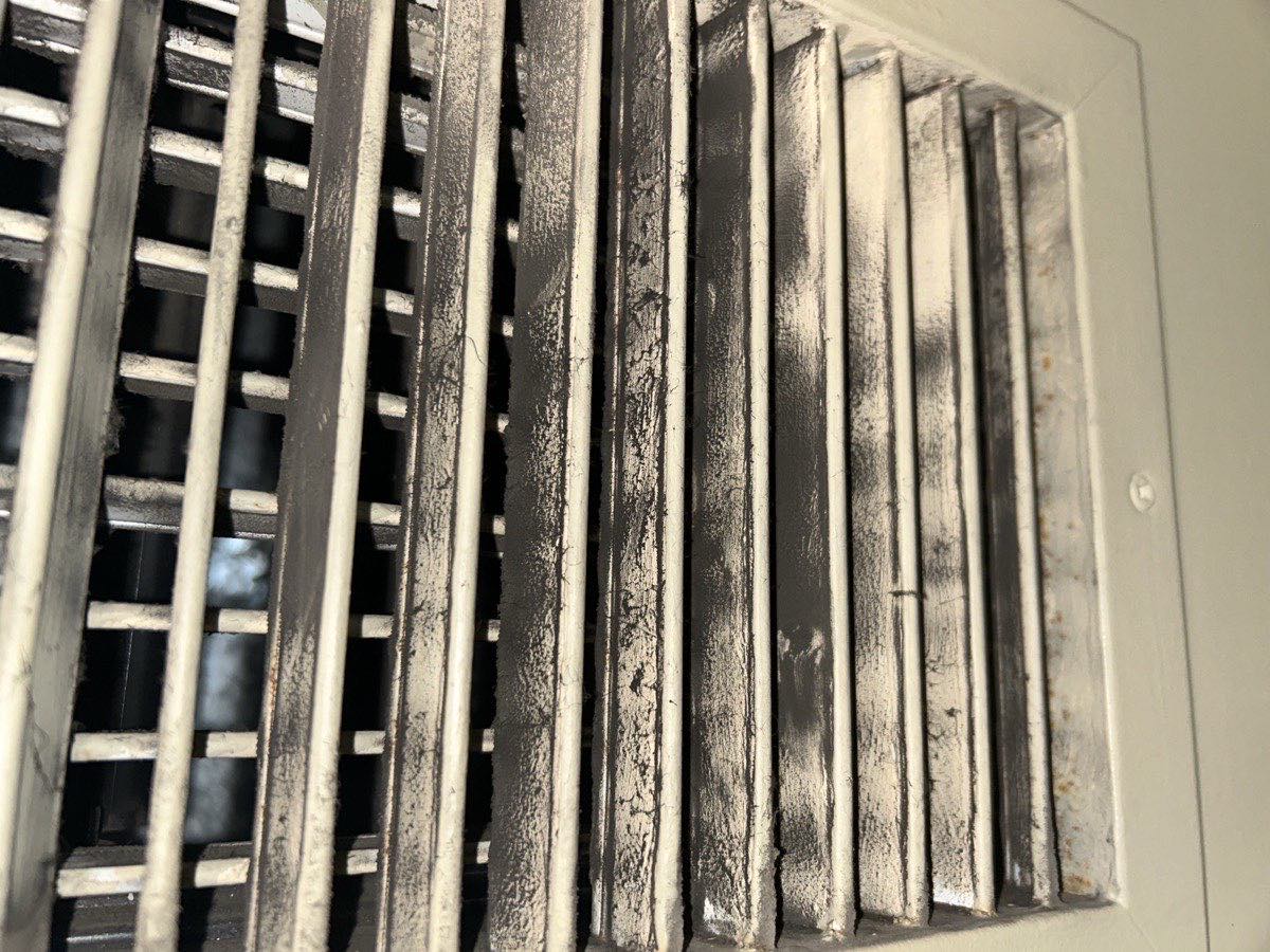 A supply register with dust caked between the fins